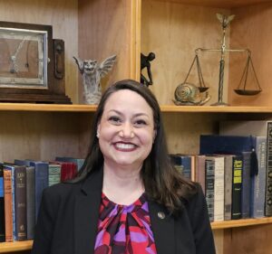Michelle Ochoa in front of bookshelves in conference room.